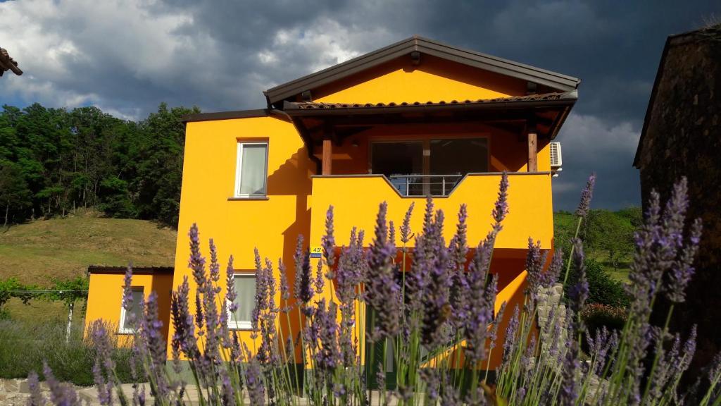 DobravljePočitniška Hiša的黄色房子前面有紫色的花