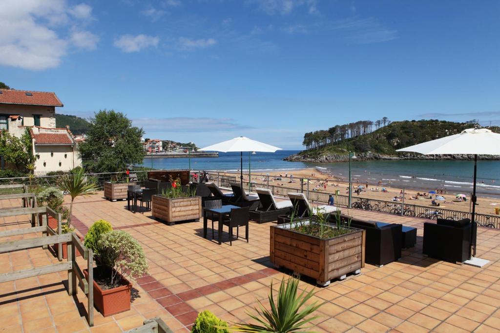 雷凯蒂奥米特罗库瓦酒店的一个带桌子和遮阳伞的庭院和一个海滩