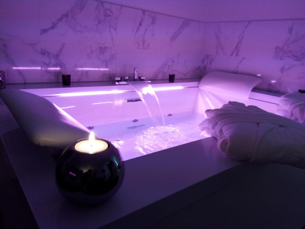 多勒La Pause Romantique的紫色客房内的浴缸配有蜡烛