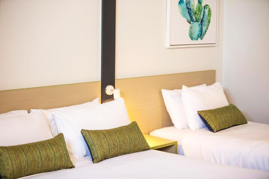 班克斯镇Nightcap at Hume Hotel的配有白色和绿色枕头的酒店客房的两张床