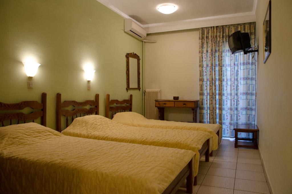 普托莱迈达Hotel Costis的酒店客房设有三张床和窗户。