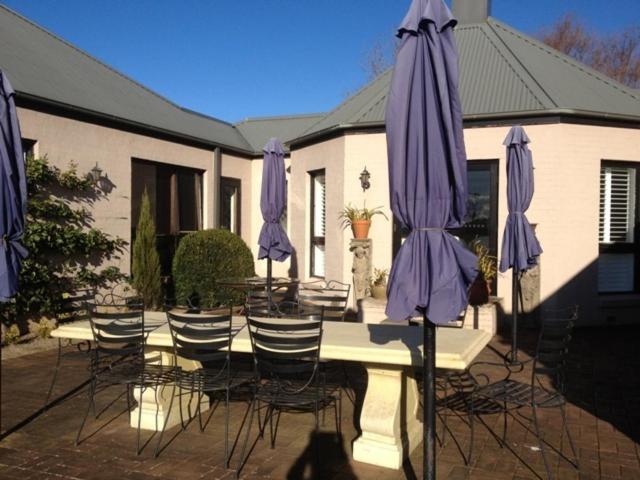 罗伯逊格林门住宿加早餐酒店的一组桌子和椅子,配有紫色雨伞