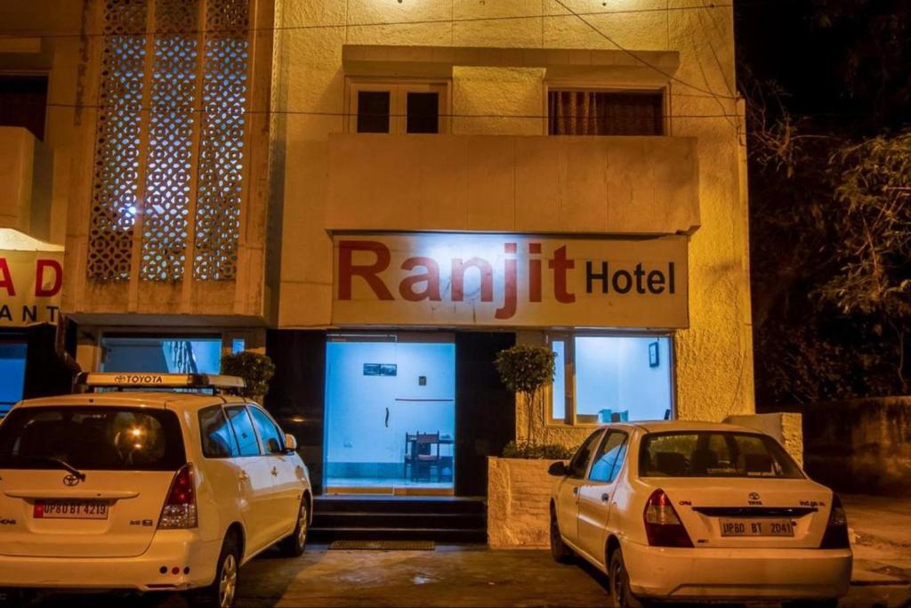 阿格拉Hotel Ranjeet的夜间在酒店门前停放两辆车