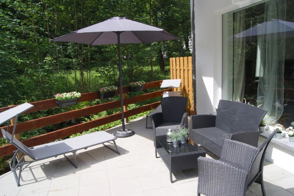 锡默拉特Ferienwohnungen TalBach的庭院配有桌椅和遮阳伞。