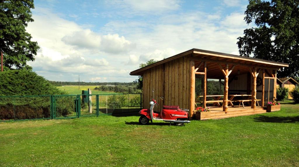 TreimaniTreimani Country House的停在草地上的带红色摩托车的小棚子