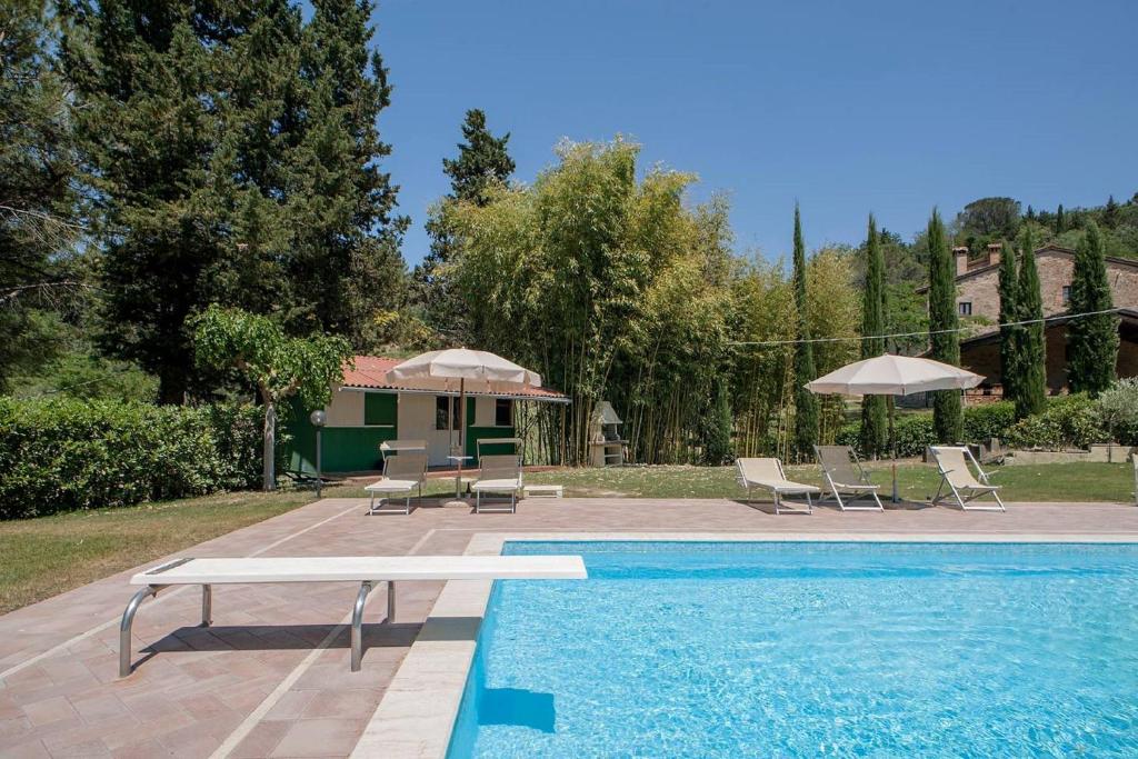泰里乔拉Azienda Agricola e Agriturismo Vallorsi的房屋旁的游泳池配有椅子和遮阳伞