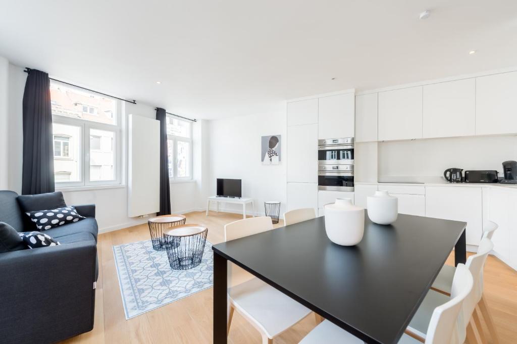 布鲁塞尔Smartflats - Toison d'Or的厨房以及带黑色桌椅的起居室。