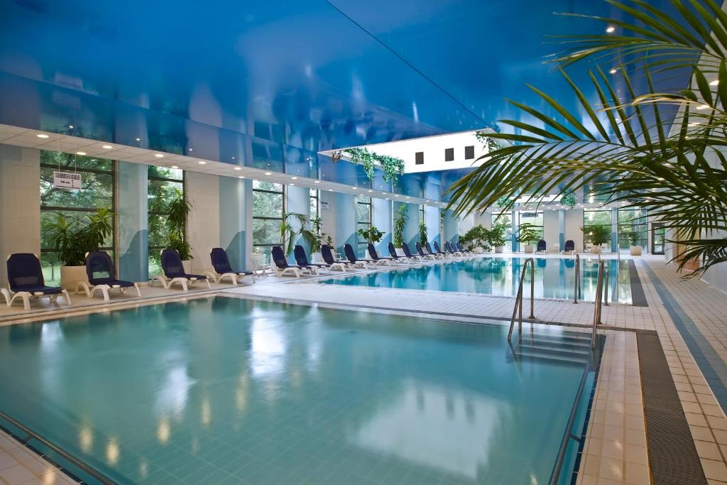 布达佩斯贺莉亚丹乌比斯酒店的一座带椅子和植物的酒店游泳池