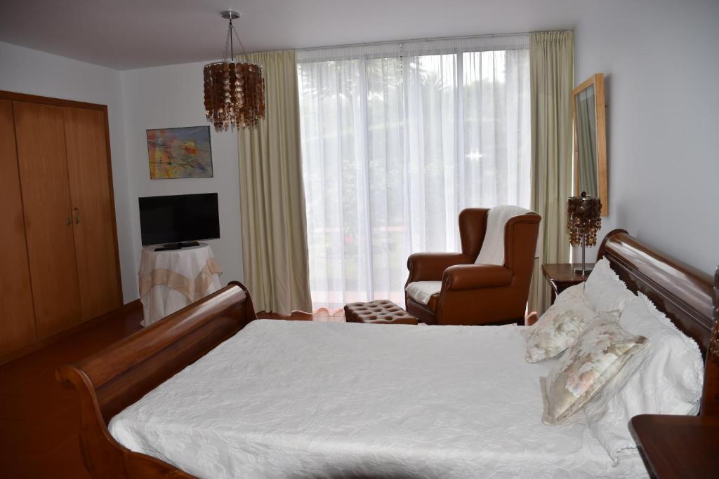 卡罗拉Caloura Camellia House的卧室配有床、椅子和窗户。