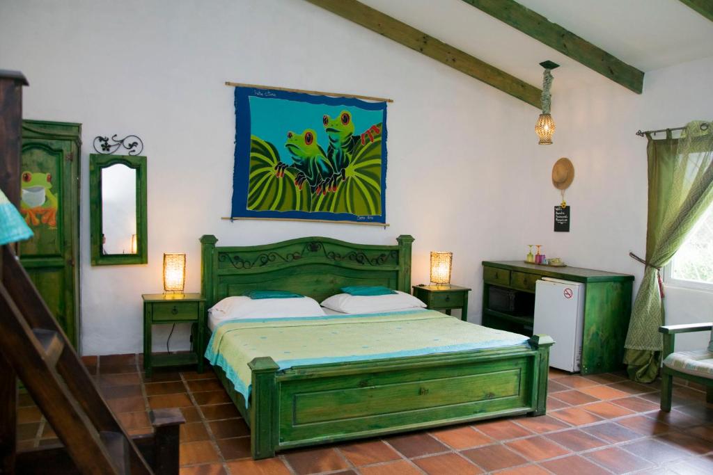 阿拉胡埃拉Villa Margarita的一间卧室配有一张绿色的床,墙上挂着一幅画