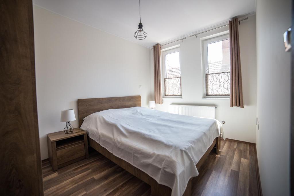 久洛Boka Apartmanház的一间白色卧室,配有床和2个窗户