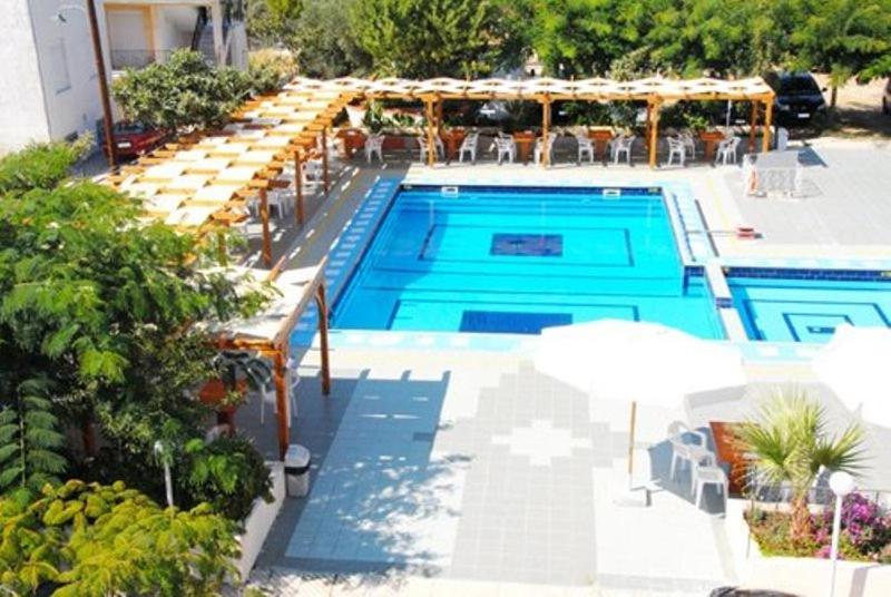 圣帕拉斯凯维Hotel Aphroditi的游泳池旁设有桌子和遮阳伞