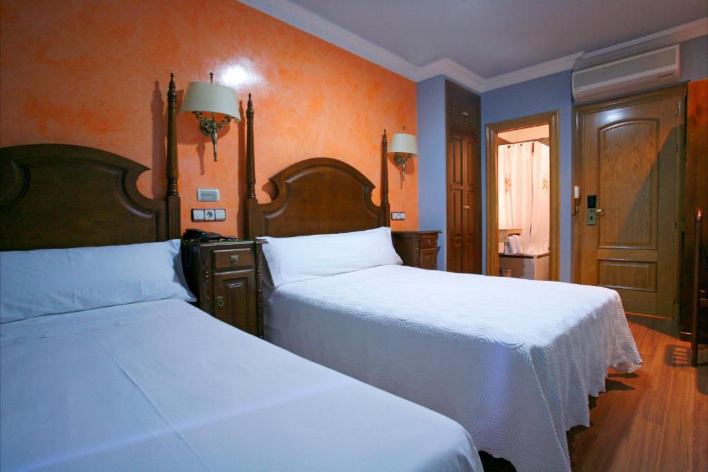 马德里维多利亚II旅馆的卧室设有两张床铺和橙色墙壁