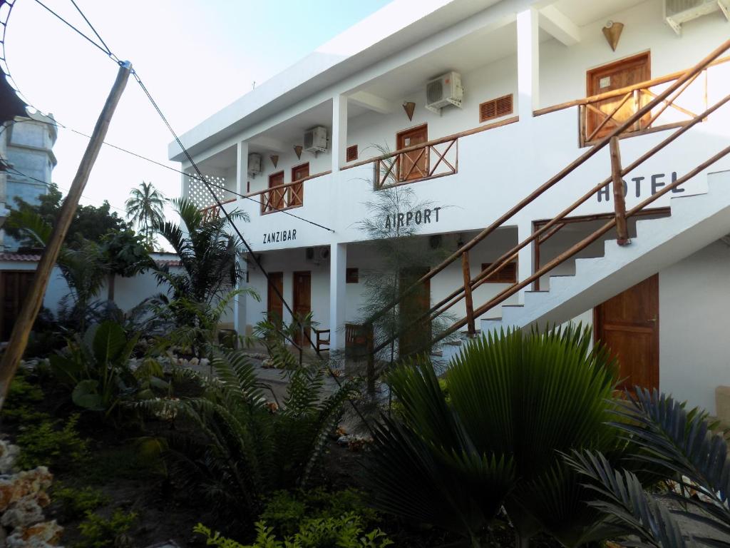 桑给巴尔27 Cafe Zanzibar Airport Hotel的前面有楼梯和植物的建筑
