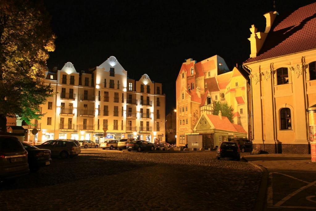 波兹南Śródka Boutique Hotel的夜间有建筑物和汽车的城市街道