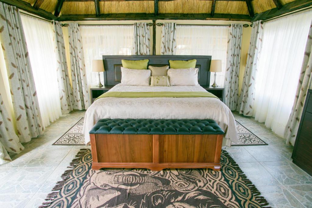 哈拉雷艺术山林小屋的一间卧室配有一张大床和绿色长凳