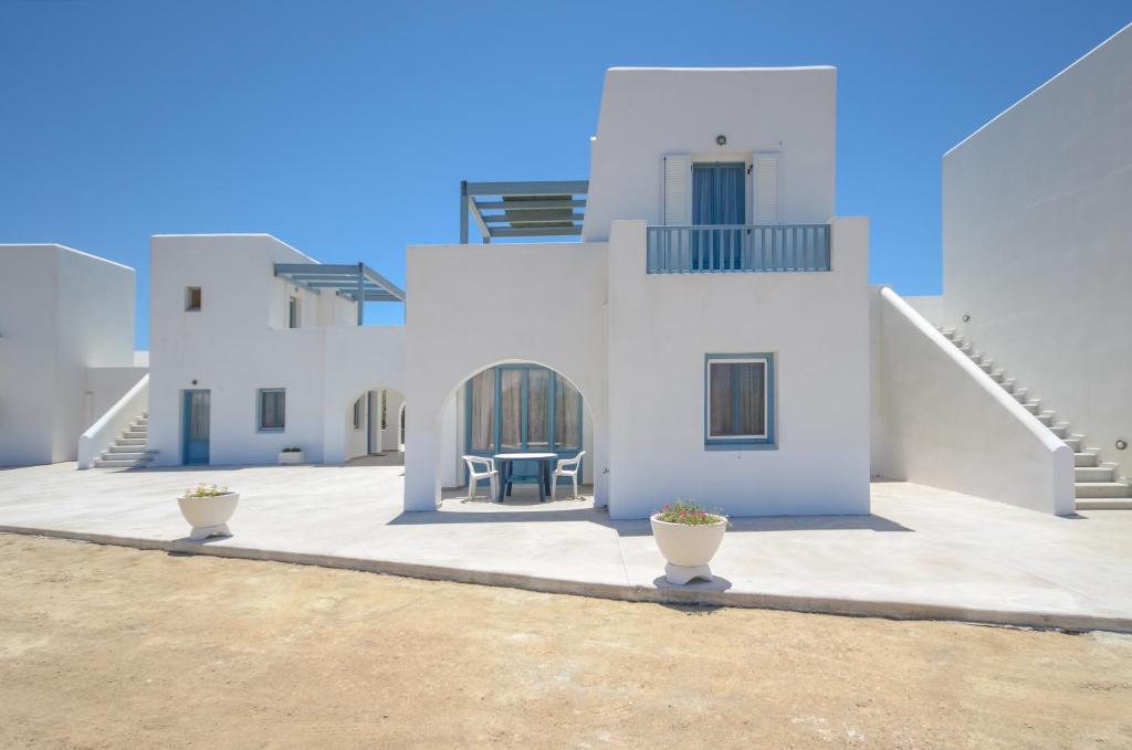 纳克索乔拉Apartments Naxos Camping的庭院内带两把椅子的白色房子