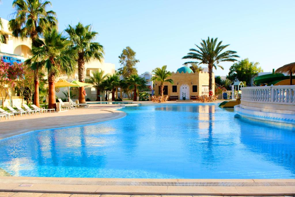 米多恩The Ksar Djerba Charming Hotel & SPA的度假村内一座种有棕榈树的大型游泳池