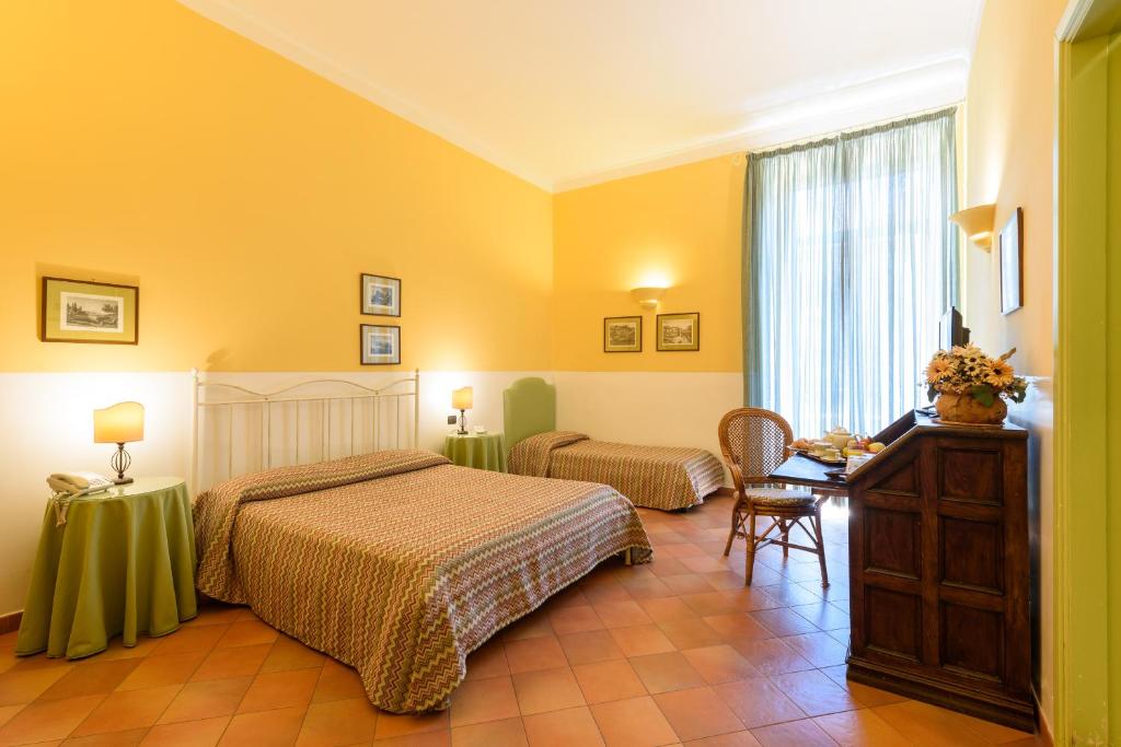 那不勒斯梅尔杰利纳酒店的一间卧室设有两张床、一张桌子和一个窗口。
