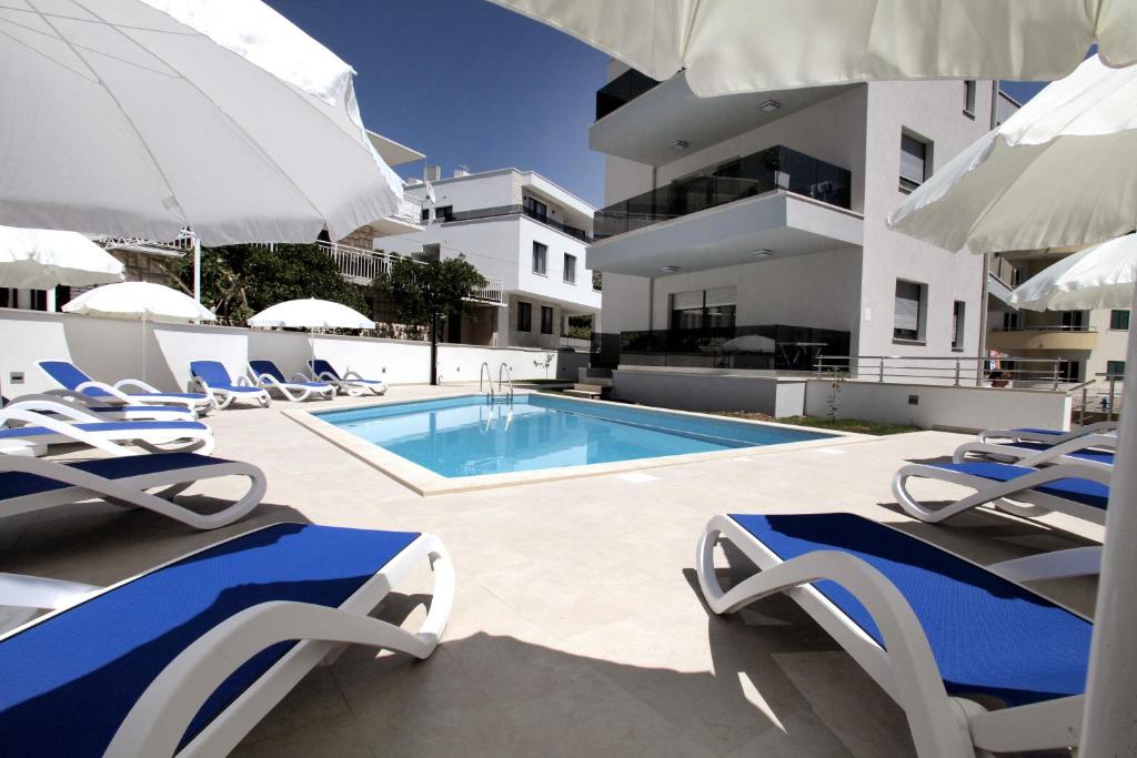 特罗吉尔Apartments Villa Aquamarie的一座带椅子和遮阳伞的游泳池位于一座建筑旁边