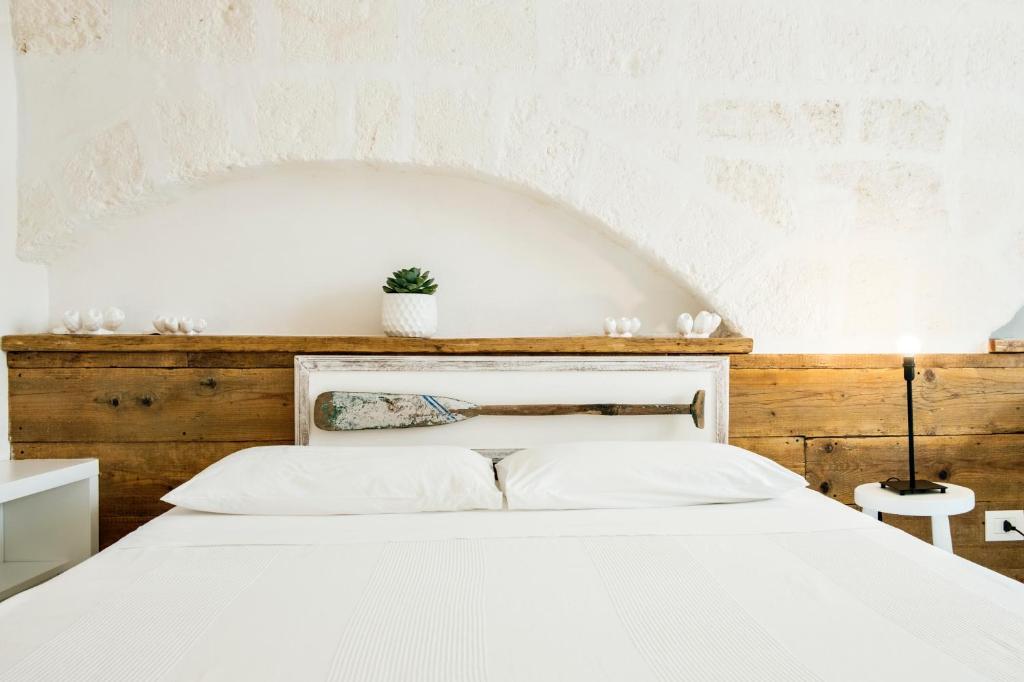 莫诺波利Borgo Albergo Capozzi 37的卧室配有白色的床和木制床头板