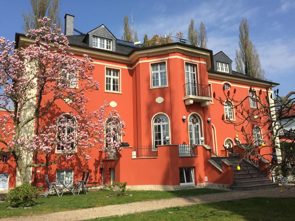 德累斯顿Villa am Park Apartment的一座大型的橙色建筑,有树
