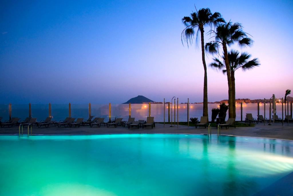厄尔梅达诺Kn Hotel Arenas del Mar Adults Only的黄昏时,游泳池里种有棕榈树,大海