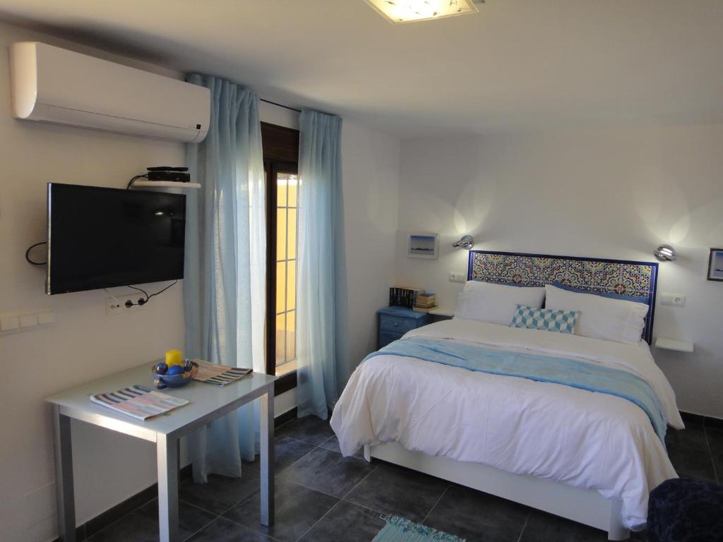 阿洛拉Casa Oasis的一间卧室配有一张床、一张桌子和一台电视。