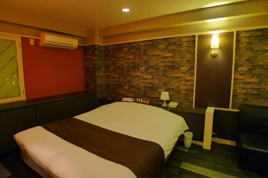 厚木高尔夫III厚木酒店（仅限成人） 的一间卧室设有一张床和砖墙