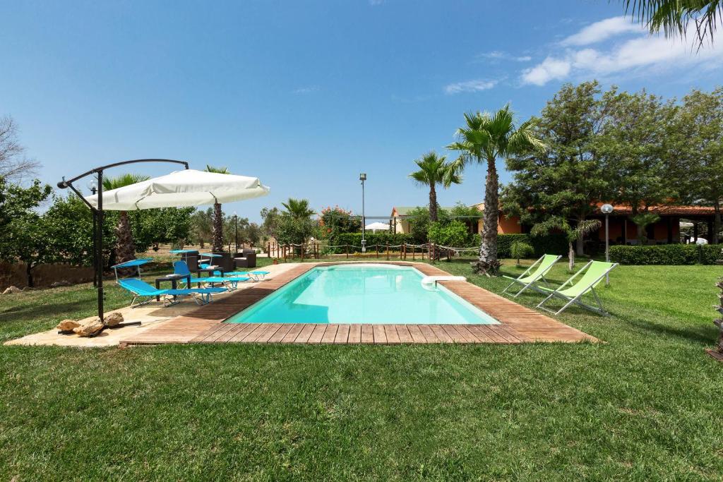 马蒂诺Dependance di Villa Dea by BarbarHouse的庭院内的游泳池配有椅子和遮阳伞