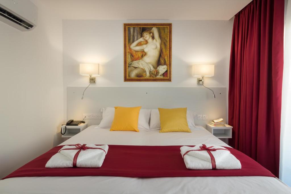 拉纳卡Art & Wine Studios and Apts的一间卧室配有红色窗帘和绘画的床