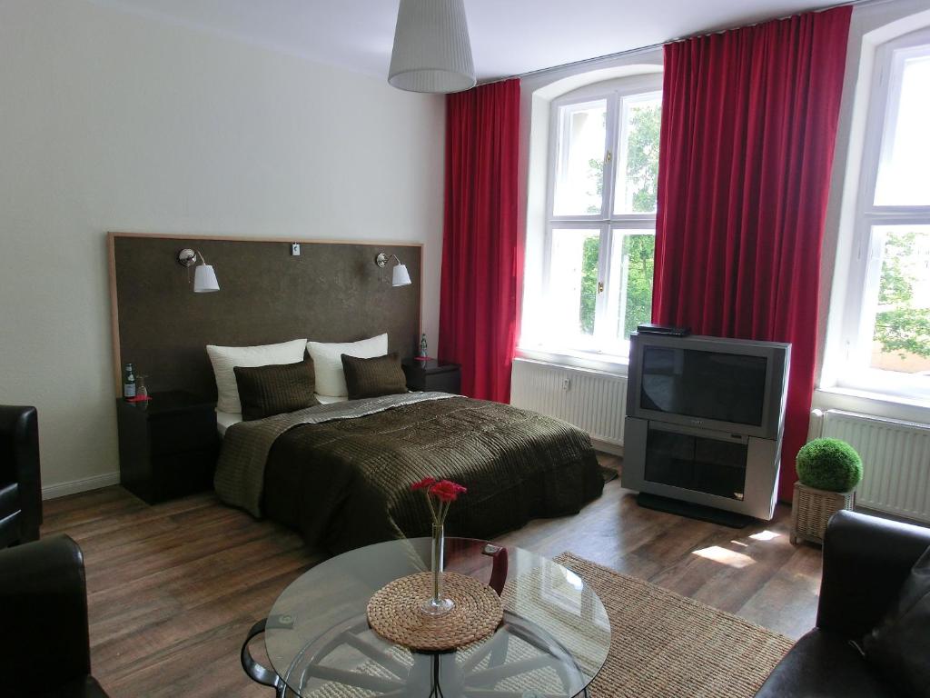 波茨坦基斯弗莱尔公寓酒店的一间卧室配有一张带红色窗帘的床和电视。
