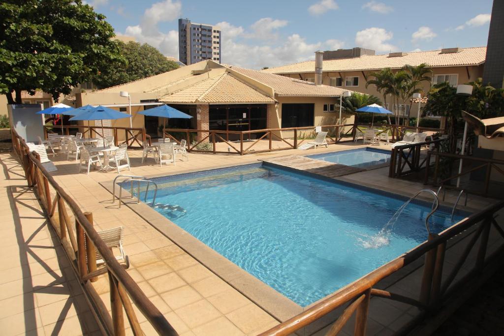 阿拉卡茹波萨达度索酒店的一座大楼内的游泳池,配有椅子和遮阳伞