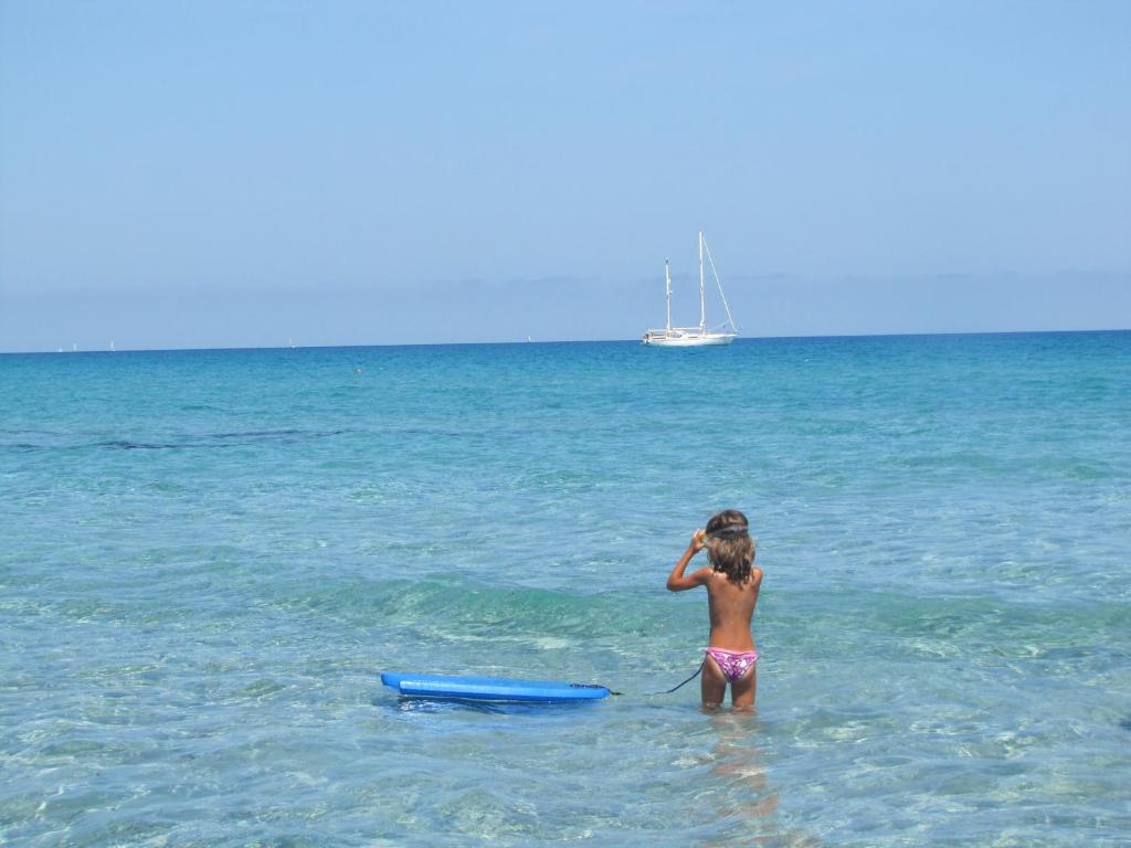 西尼斯科拉Villaggio Camping Calapineta的一只小女孩站在海洋里,手持木筏