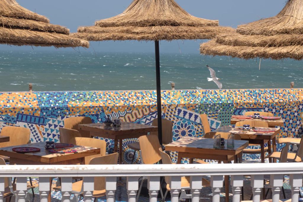 索维拉Salut Maroc!的海滩上设有桌子和遮阳伞的餐厅