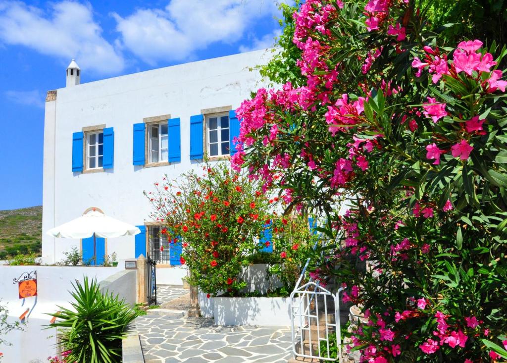凯瑟拉玛格丽塔酒店的白色的建筑,有蓝色的窗户和粉红色的鲜花