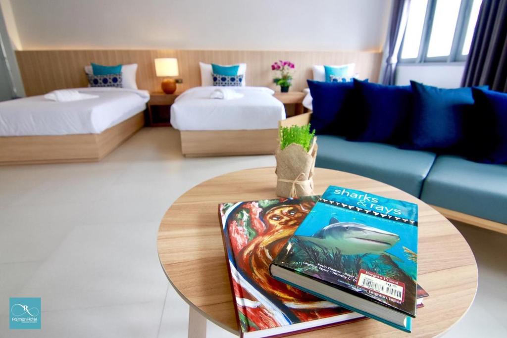 素叻Rajthani Hotel - SHA Certified的客房设有两张床和一张桌子,并备有书籍