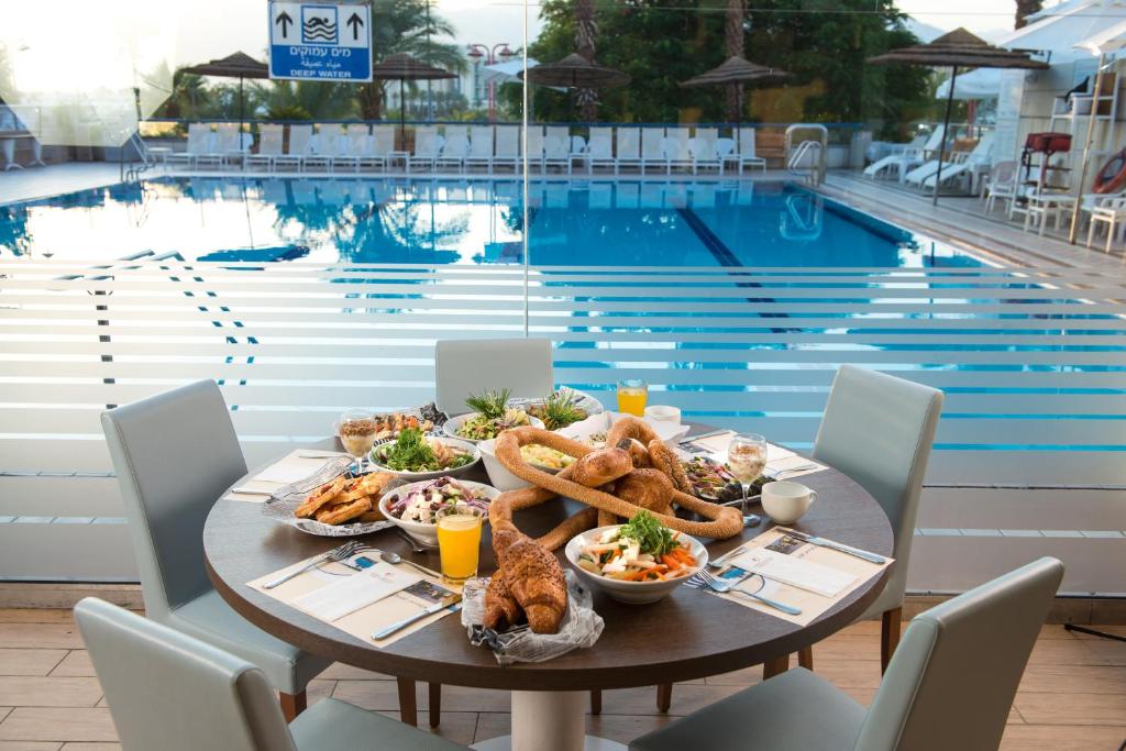 埃拉特Hotel Astral Nirvana Club- Half Board的游泳池旁带食物的桌子