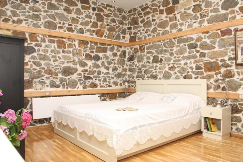 萨莫色雷斯Traditional Houses Atzanou的卧室配有白色的床和石墙