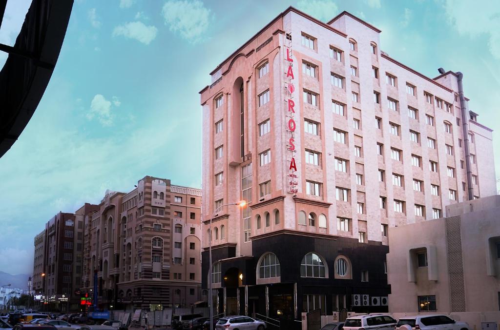 马斯喀特阿曼拉罗莎酒店的粉红色的建筑,旁边标有标志