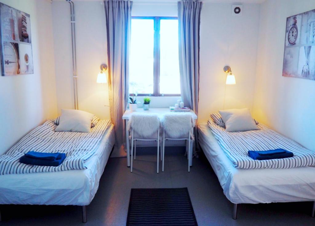 诺尔雪平Turistgårdens vandrarhem i Norrköping的客房设有两张床、一张桌子和一扇窗户。