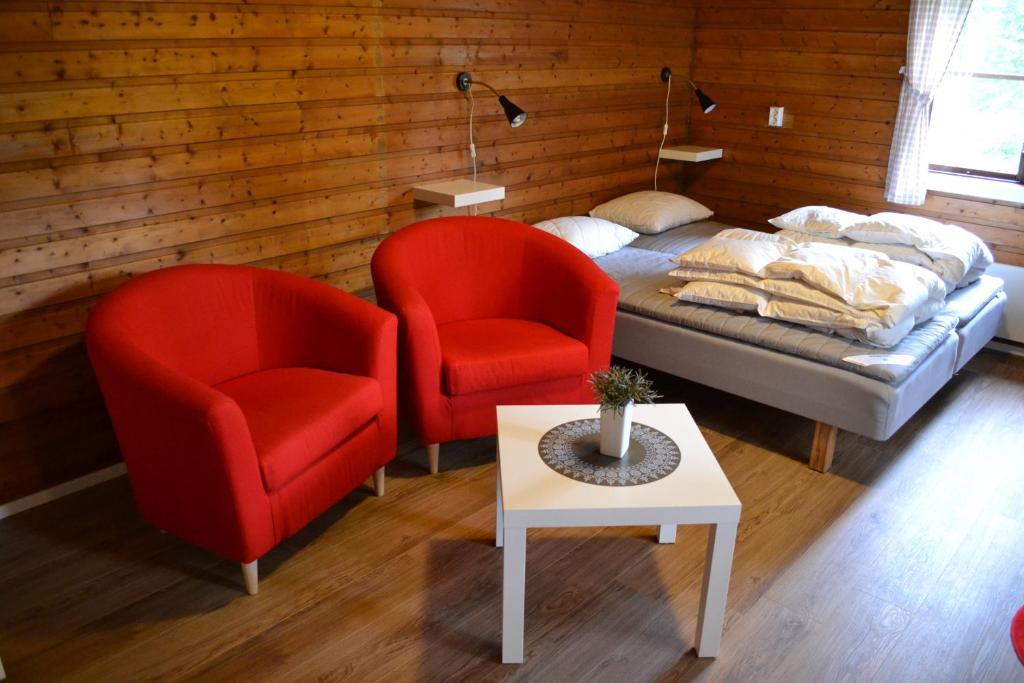 DoroteaDoro Camp Lapland的一间卧室配有两张红色椅子、一张床和一张桌子