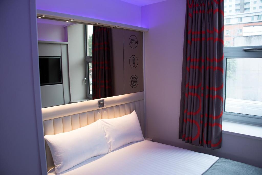 伦敦伦敦威斯敏斯特波特A酒店的一间卧室配有一张带窗户的床和一张白色的四柱床