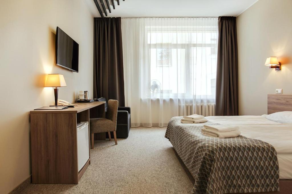 维尔纽斯旧城特里奥酒店的配有一张床、一张书桌和一扇窗户的酒店客房