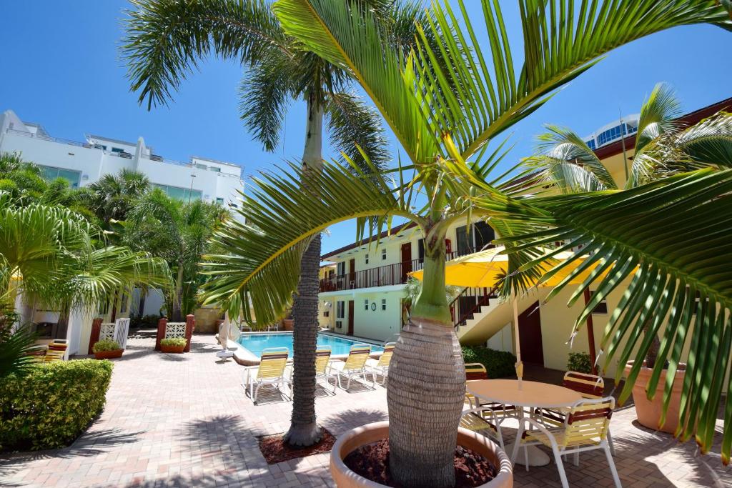 帕诺滩冲浪赛德度假酒店的庭院设有桌子和棕榈树,还设有游泳池