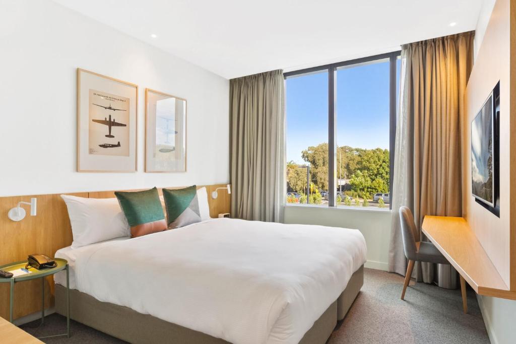 悉尼悉尼机场曼特拉酒店的一间设有大床和窗户的酒店客房
