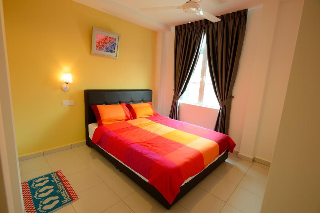 马六甲法摩萨2号民宿的一间卧室配有带橙色枕头的床和窗户。