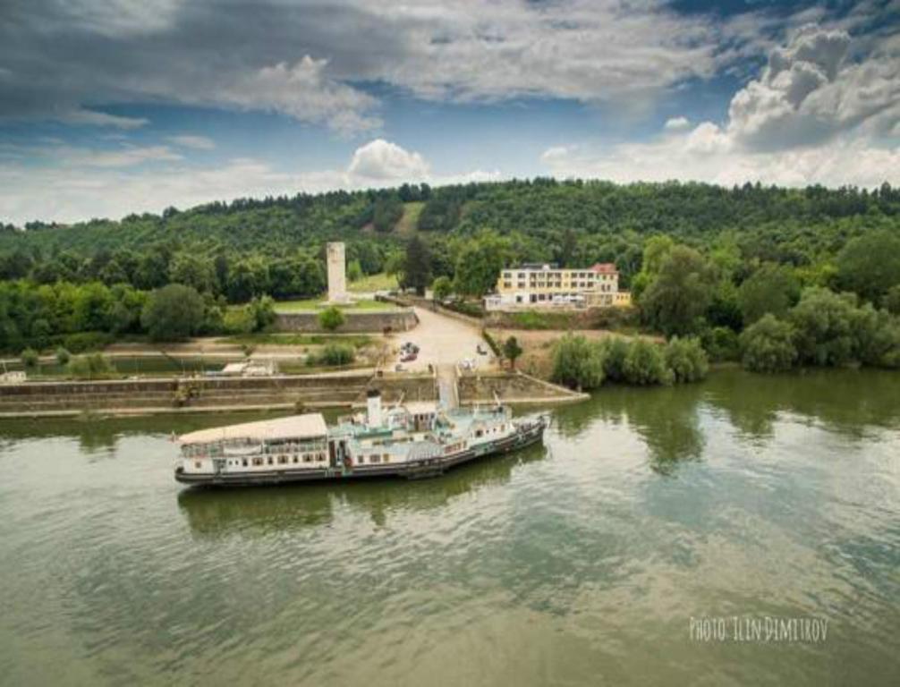 KozloduyХотелски комплекс Радецки град Козлодуй的一艘船停靠在海滩旁的河流上