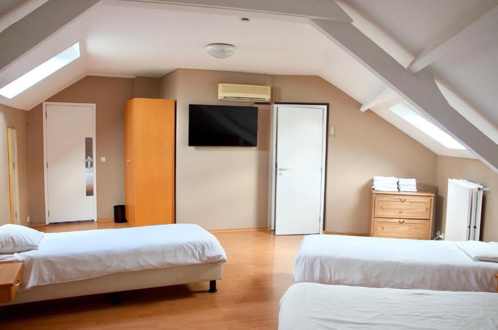 布鲁塞尔腓特烈斯贝酒店的一间卧室设有两张床,墙上配有电视。