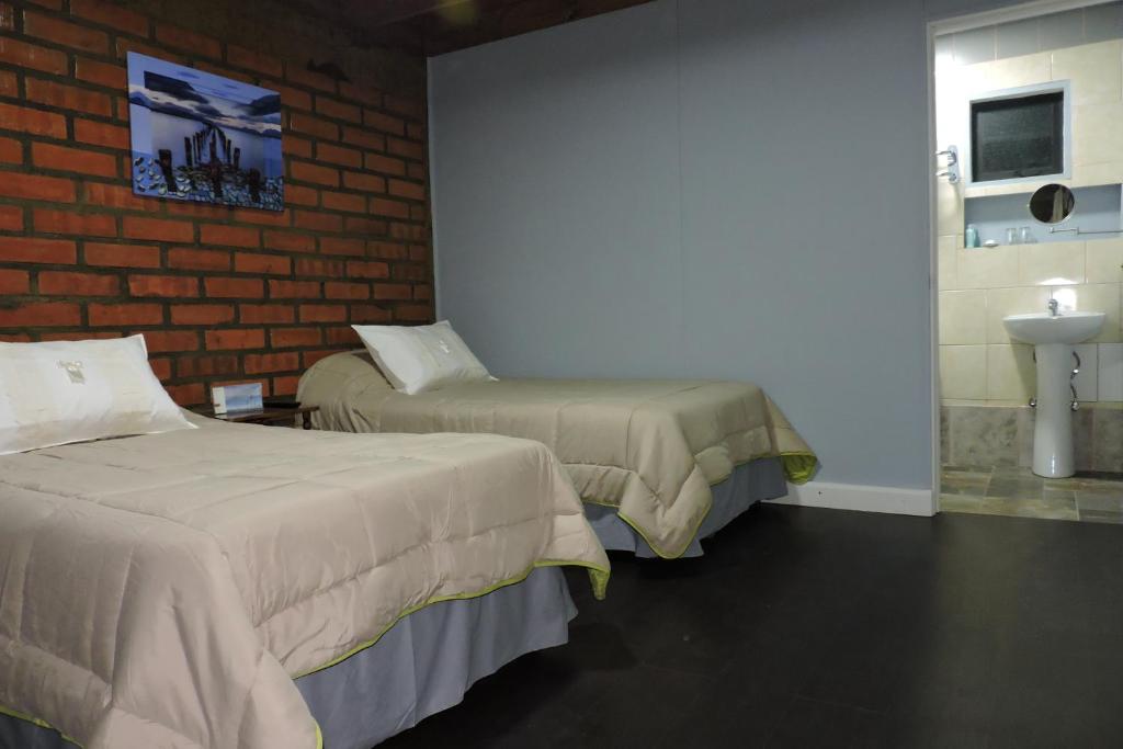 纳塔列斯港Maromava Patagonia的带两张床、水槽和砖墙的客房
